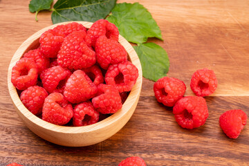 Raspberry fruit on wooden bowl in Wooden background, Raspberries with leaves on Wooden background.
