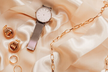 Women's jewelry earrings, trendy jewelry, watches, rings on a silk background.