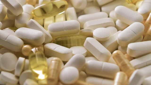 Different pills with capsules and tablets falling on white table, concept of medical treatment, slow motion. Close-up