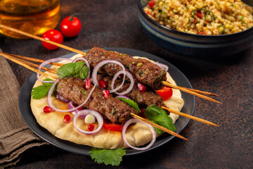Dinner woth homemade beef Kofta kebabs with coriander on pita bread with red onion, tomatoes and...
