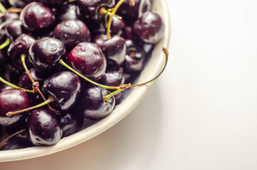Closeup on fresh and ripe sweet cherries on a white ceramic plate