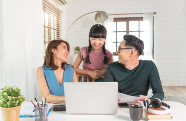 Happy Asian family colleagues work with laptop computer indoors in office talking with each other.