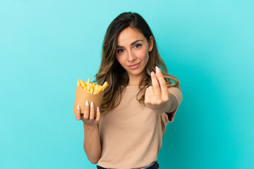 Young woman holding fried chips over isolated background making money gesture