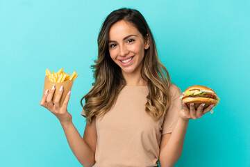 Young woman holding fried chips  and burger over isolated background