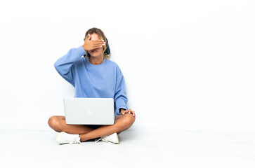 Young blonde Uruguayan girl with the laptop isolated on white background covering eyes by hands. Do not want to see something