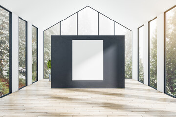 Blank white poster on black partition in the center of modern sunny houseroom with forest view from...