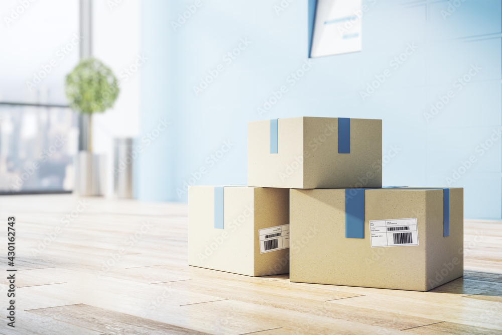 Poster delivery service concept with cardboxes with barcodes on wooden floor in empty sunny room with blue 