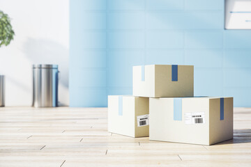 Cargo transportation service concept with cardboxes on light wooden floor in sunny office room with blue wall