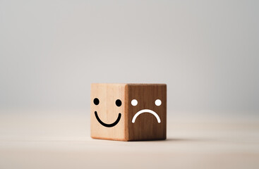 Smiley face on bright side and sadness on dark side of wooden cube block , Emotion selection and mindset concept.