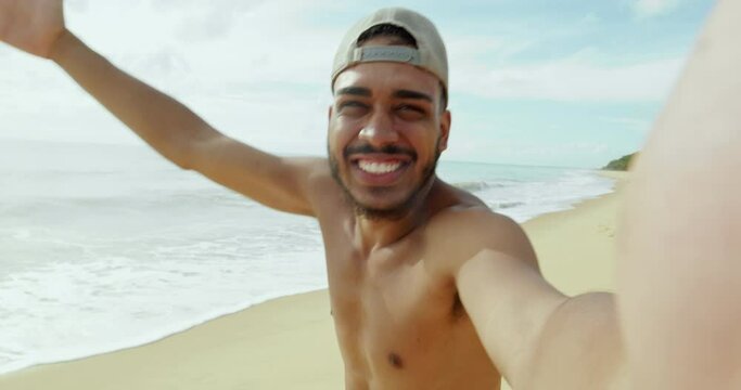Friendly young Latin American man inviting to come to Brazil, confident and smiling making a gesture with his hand, being positive and friendly. Beach from Brazil. 4K.