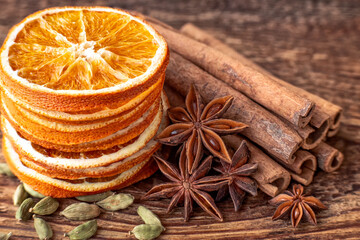 Fototapeta na wymiar Dry orange slices, anise stars, cinnamon, cardamom and roasted coffee beans on a wooden table. 