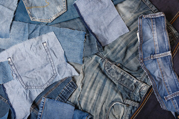 Old denim garbage background. Recycling old jeans. Old blue jeans ready for recycling on wooden table. Denim upcycle. Circular economy. Pile of discarded old blue jeans. Zero waste