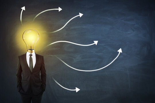Sturtup and idea concept with man in black suit with light bilb on shoulders on blackboard with arrows background