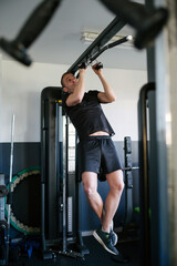 Fototapeta na wymiar Concept: sport. Athlete man in the gym. Doing pull-ups on the bar.