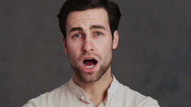 The portrait of a man biting his lip and saying wow while standing in a studio