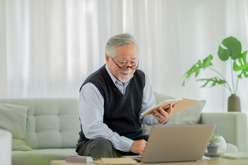 Happiness Asian senior handsome business man with white hairs hold book and learning with computer...