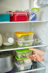 Young man puts trays in the refrigerator. The concept of preparing and storing home or restaurant food for a long time. Trendy concept