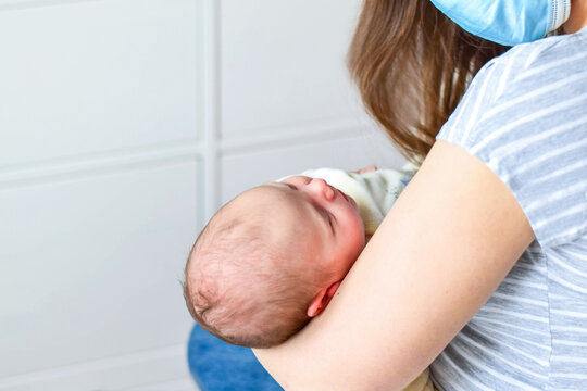 Mother In Face Mask Holding Newborn Baby And Breastfeeding Little Infant Kid In Hands. Bright Portrait Of Happy Mum And Sleeping Infant Child. Mother Hugging Her Little 1 Months Old Child At Home.