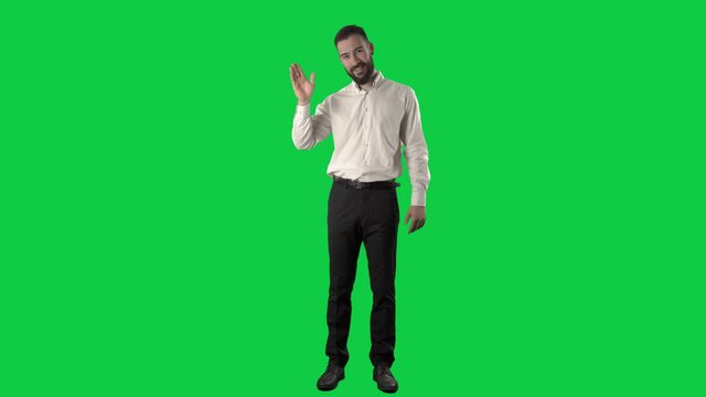 Friendly happy business man waving hand greeting and introducing himself. Full length on green screen chroma key background