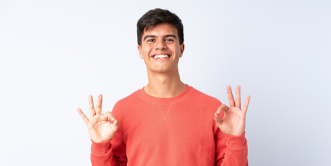 Handsome man over isolated blue background showing ok sign with two hands