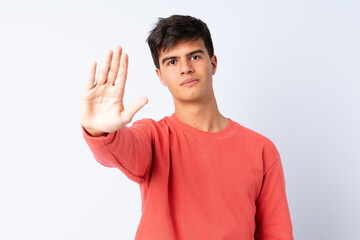 Handsome man over isolated blue background making stop gesture