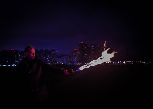 A man holding a hot sword, photo against the background of the city, in purple