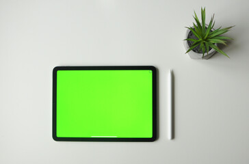 Green background mock-up on tablet device with stylus. Minimalism style top view