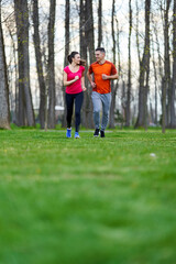 Fototapeta na wymiar Young couple running in the park