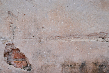 Old white cement wall that has decayed until you can see the bricks.