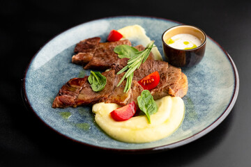 Fried beef mumm with mashed potatoes, served on a gray plate on a black background.