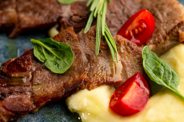 Fried beef mumm with mashed potatoes, served on a gray plate on a black background.