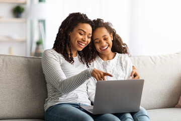 Excited african american mother and kid using laptop together