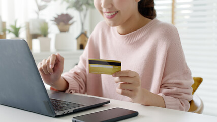 Young asian lady hold credit card in hand pay electronic money in internet online remote shopping store quarantine lifestyle at home feeling happy positive and satisfaction social distance isolate.