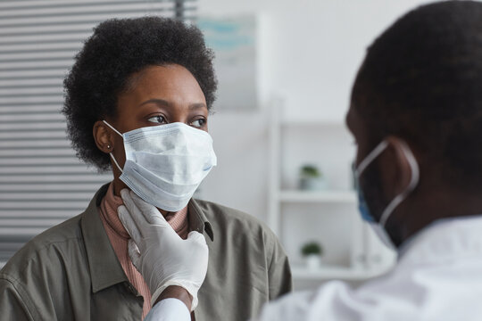 African Woman In Protective Mask Sitting At Doctor's Office While Doctor Examining Her Throat