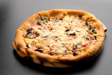 Pizza is not a wooden board. Black background. close-up.