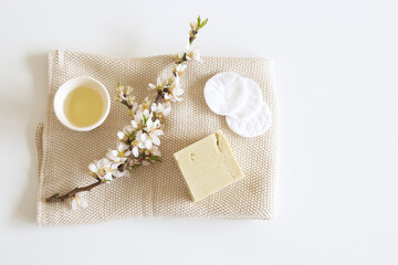 Closeup of hand made herbal soap and almond oil. Almond twigs white table background. Spa concept. Skin product mockup scene. Cosmetic product.