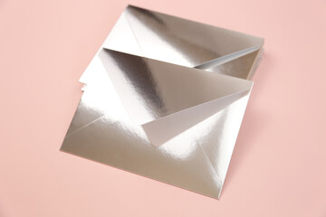 Mirror or Silver paper festive envelopes on pink background, top view. Envelopes for invitations or cash gift.