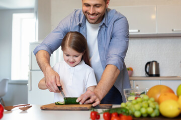 Father And Daughter Cooking Salad Cutting Vegetables Together In Kitchen