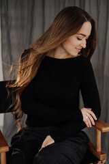 Fototapeta premium Girl Sitting on Chair in Studio Looking Away Photo