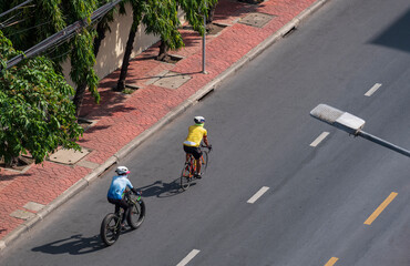 Bird's eye view of 2 cyclist man exercising by cycling on asphalt road in the city at morning time