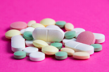 Fototapeta na wymiar Many multicolored vitamins and pills on a pink background copy space, close-up