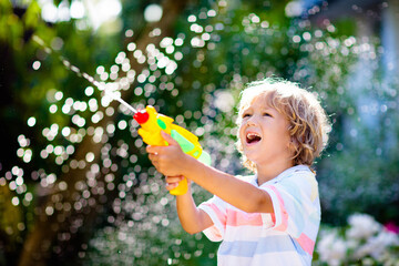 Kids with water gun toy in garden. Outdoor fun.