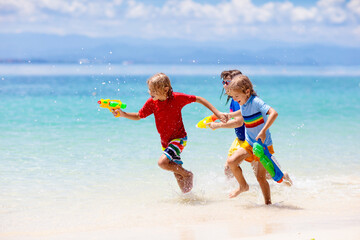Child with toy water gun. Kids vacation beach fun.
