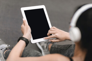 Athletic woman using digital tablet with black screen during workout outdoors