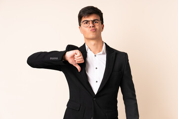 Businessman over isolated beige background showing thumb down sign