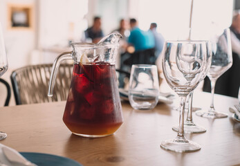 Jarra de litro de sangría hecha con vino tinto y zumos frutales, con dos copas en un restaurante