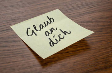 Sticky note with the text Believe in you in german - Glaub an dich