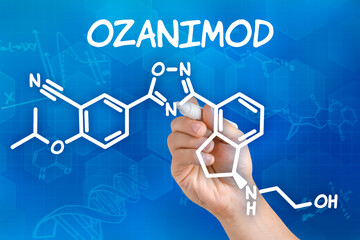 Hand with pen drawing the chemical formula of Ozanimod