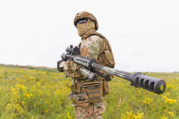 Equipped and armed special forces soldier with riffle standing in the field