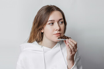 Loss of smell. Close up portrait of caucasian young woman sniffing coffee grains isolated on white background. Consequences of the coronavirus